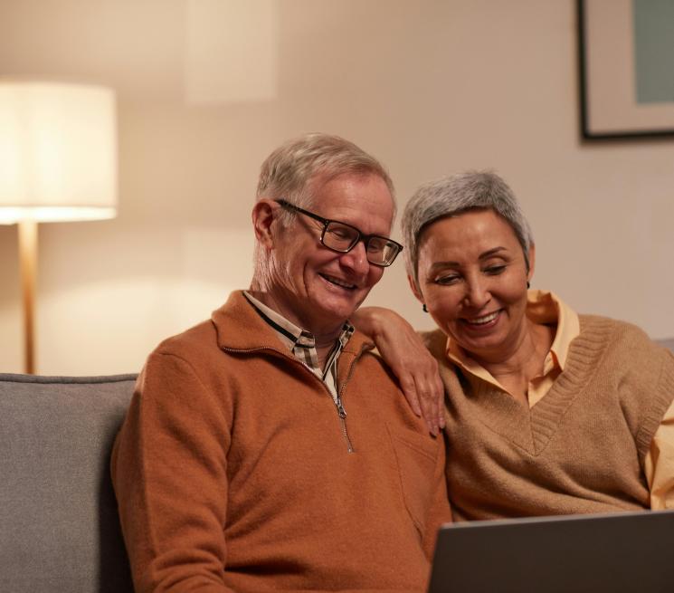 para seniorów siedzi na kanapie i patrzy w laptopa