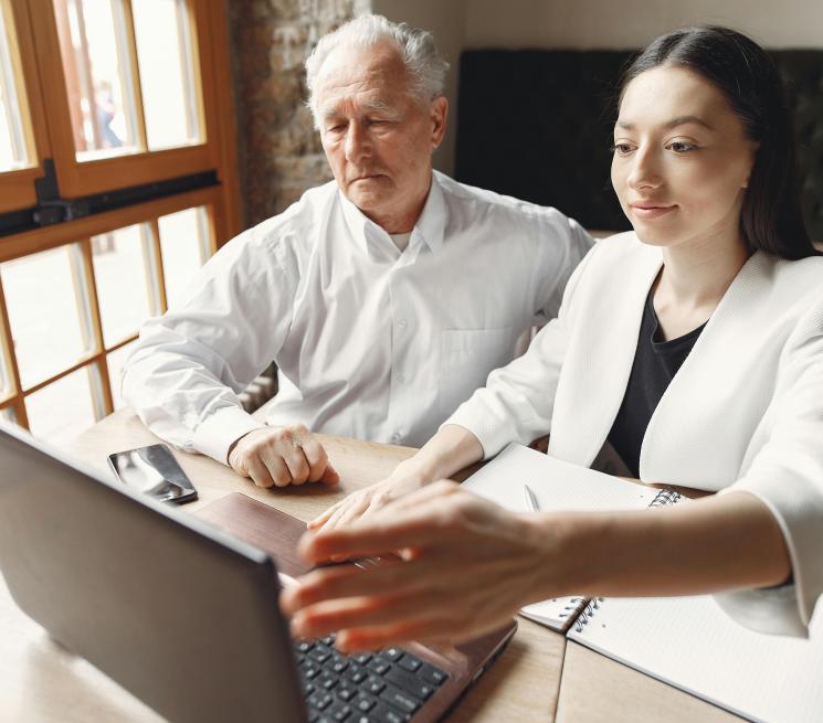 starszy mężczyzna młoda kobieta patrzą w laptopa