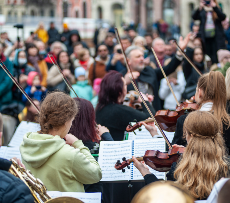 grupa osób wykonuje koncert muzyki klasycznej w plenarze na ulicy