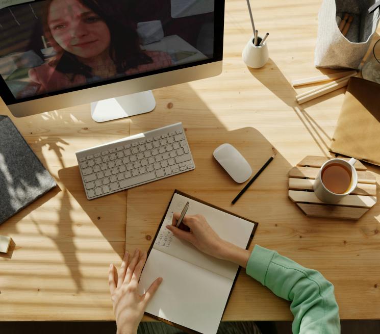 szkolenie online kobieta siedzi przy biurku notuje na ekranie monitora prowadząca szkolenie