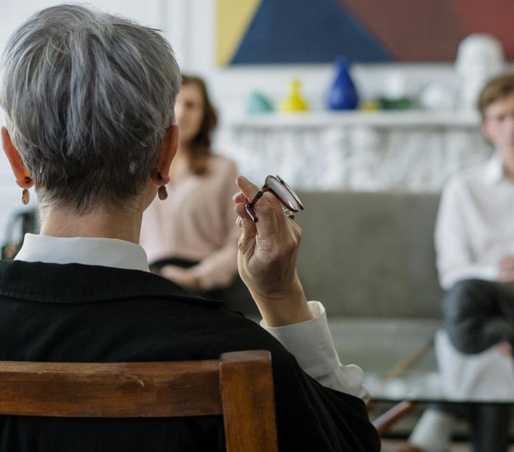 zdjęcie osoba siędząca tyłem prowadzi rozmowę z dwójką osób