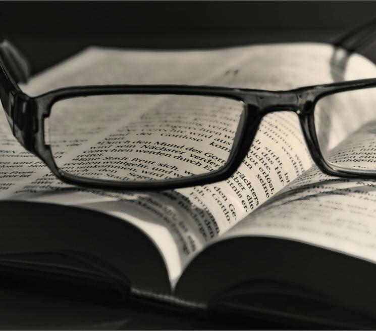 zdjęcie okulary w czarnej oprawce leżą na otwartej książce