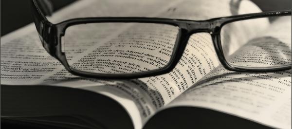 zdjęcie okulary w czarnej oprawce leżą na otwartej książce