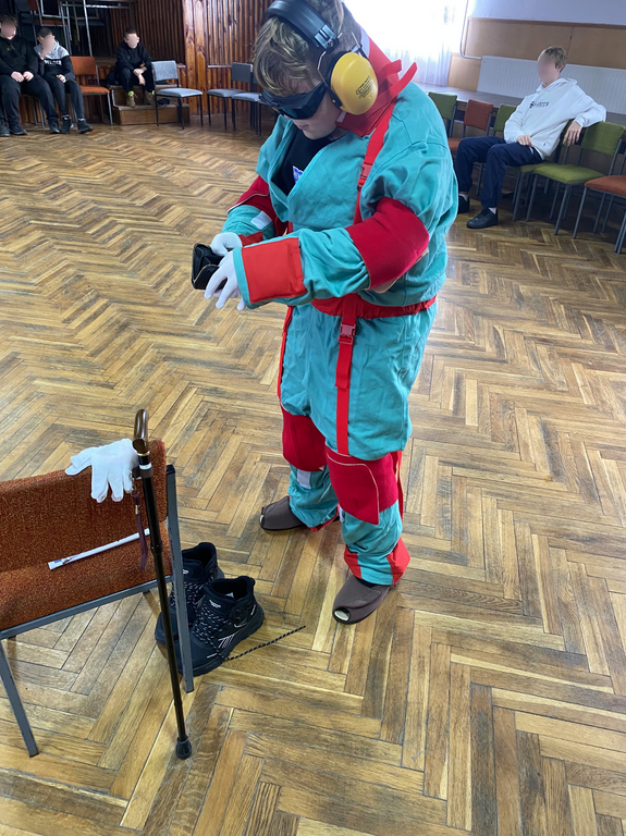 zdjęcie chłopiec w kombinezonie geriatrycznym szuka w portfelu monet