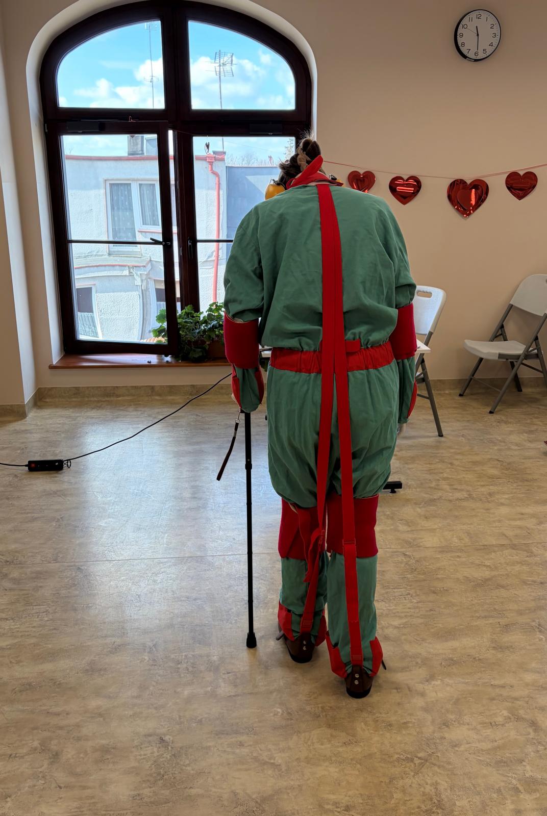 zdjęcie osoba ubrana w kombinezon geriatryczny spaceruje po sali
