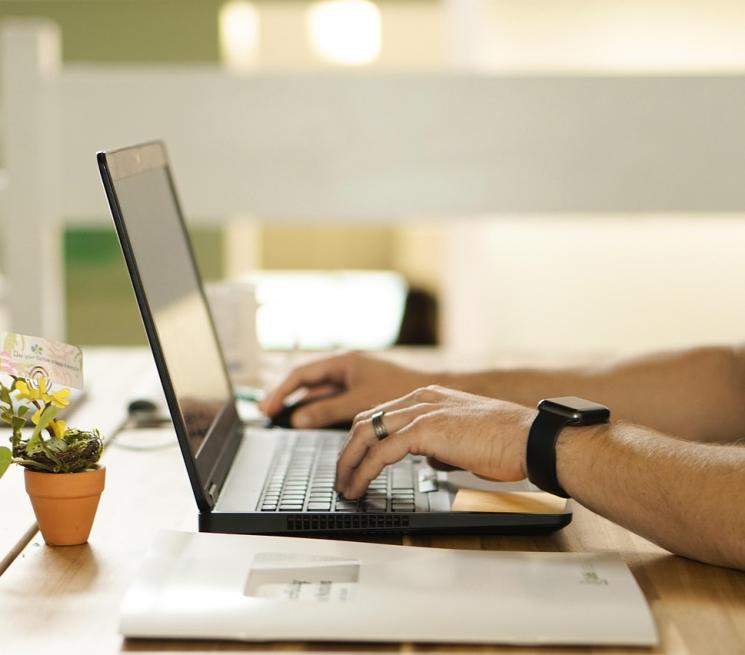 zdjęcie dłonie mężczyzny piszącego na klawiaturze laptopa