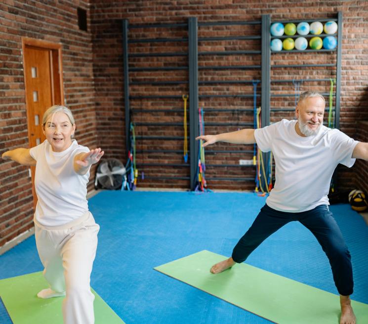 zdjęcie para seniorów ćwiczy na matach w sali gimnastycznej