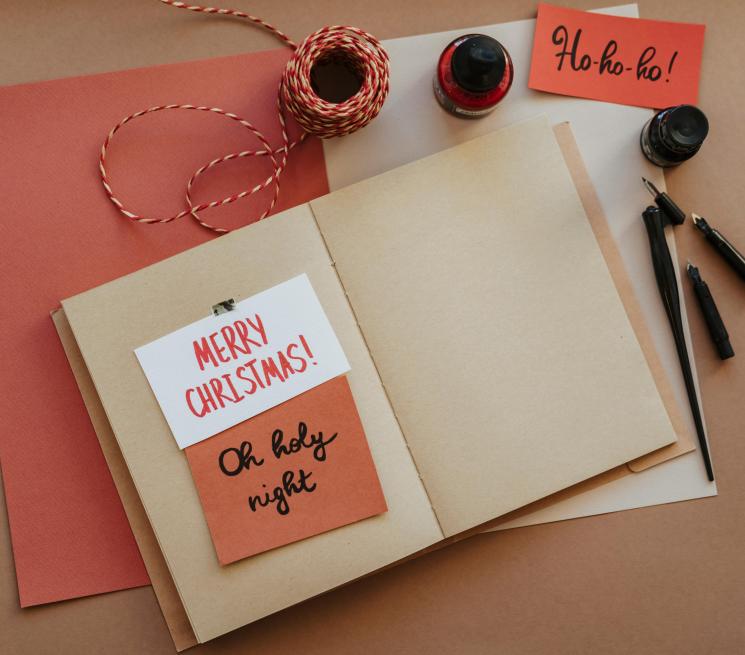 zdjęcie otwarty notes na nim biało-czerwone karteczki z napisami świątecznymi 