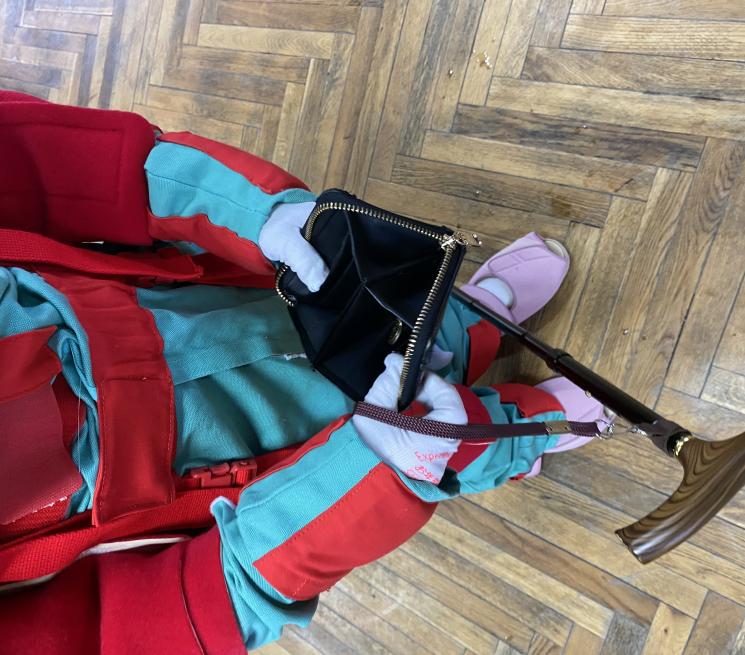 zdjęcie osoba w kombinezonie geriatrycznym trzyma laskę i otwarty portfel