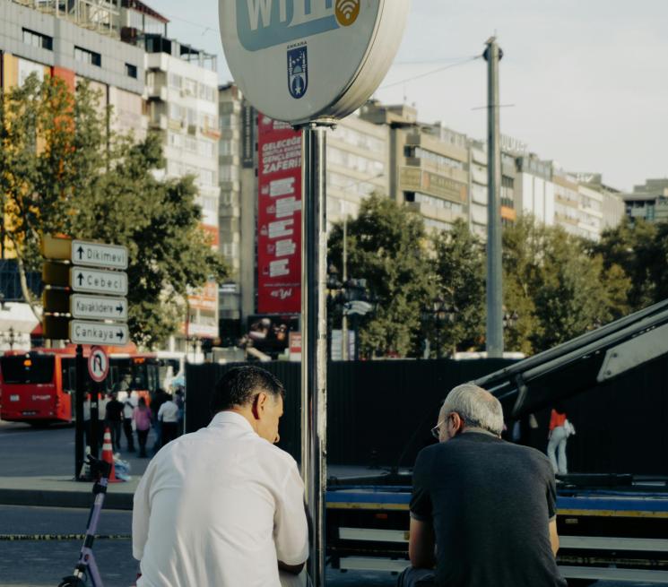 zdjęcie dwóch mężczyzn siedzi na barierce przy znaku z darmowych WIFI