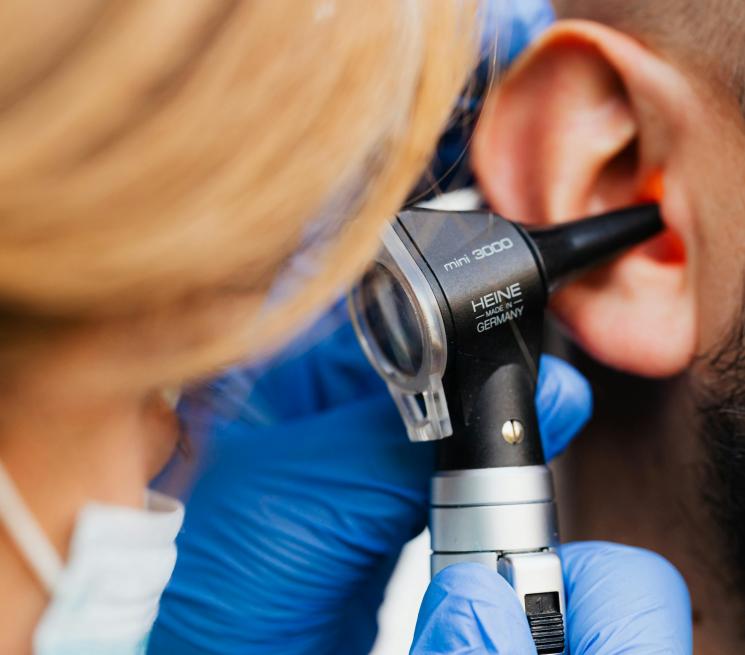 zdjęcie lekarka bada uchu przez czarny otoskop laryngologiczny