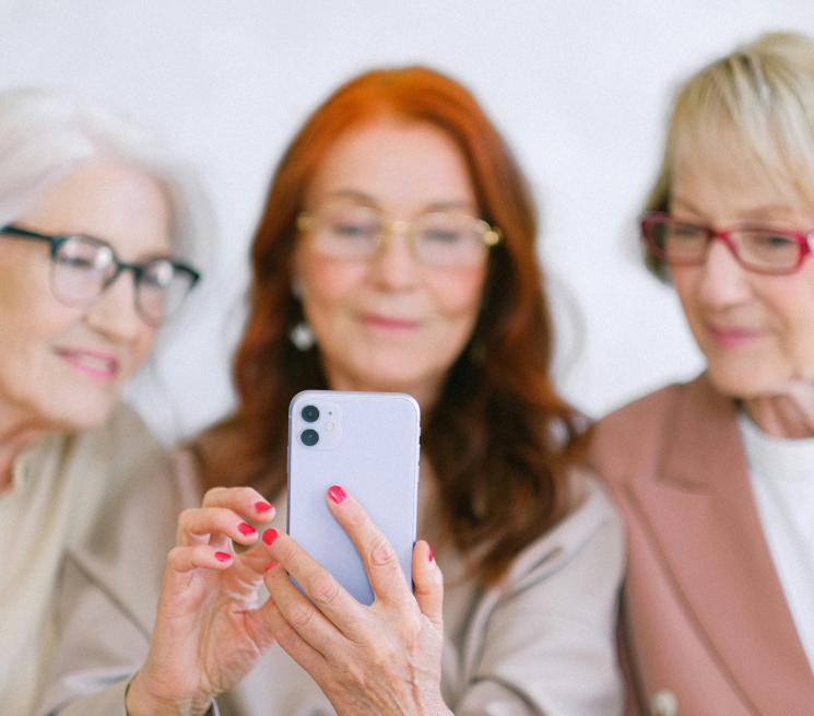 zdjęcie trzy starsze kobiety patrzą w jeden smartfon