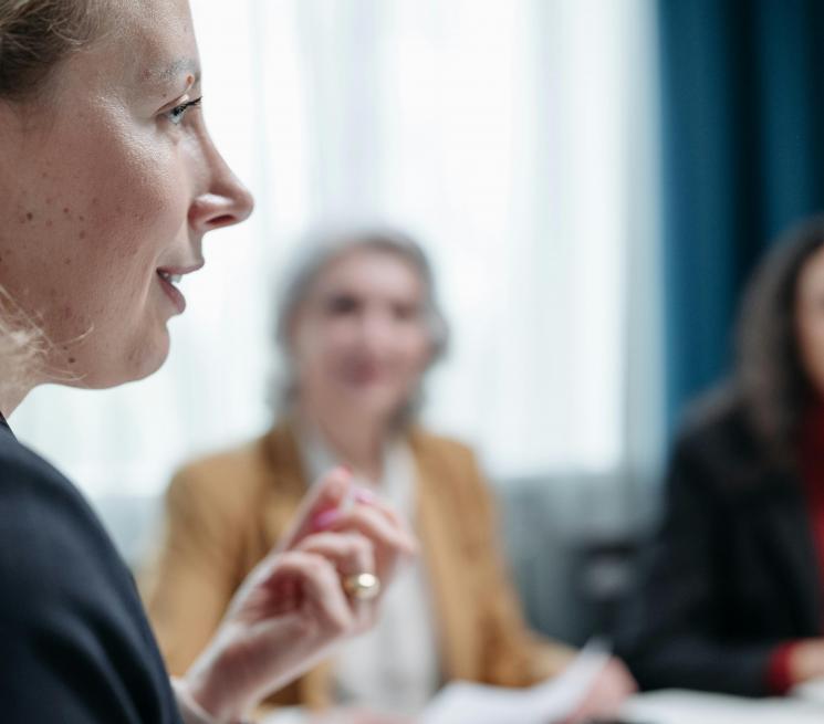zdjęcie młoda kobieta profilem w tle rozmazane postaci dwóch innych kobiet