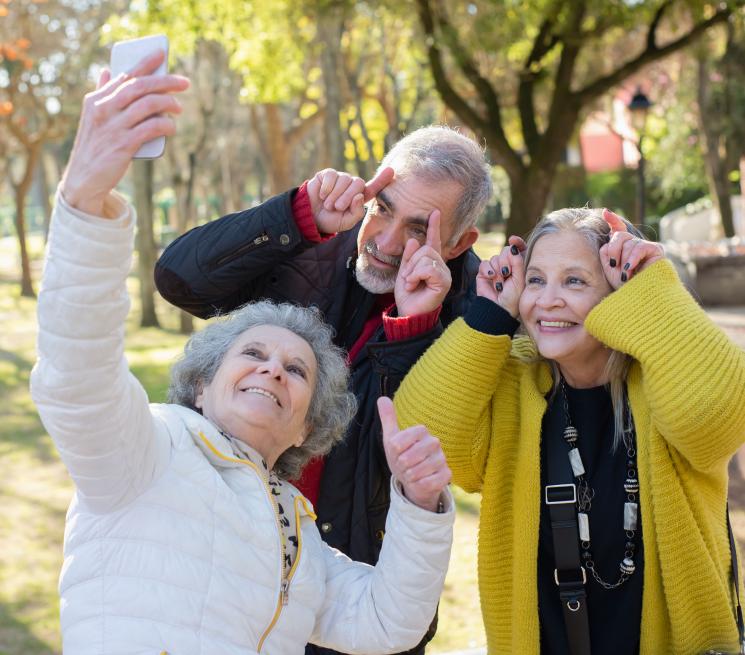 zdjęcie trójka seniorów dwie kobiety i jeden mężyzna uśmiechnięci pozują do zdjęcia selfie