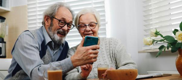 zdjęcie para seniorów siedzących przy stole patrzy w telefon
