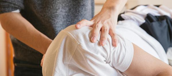 zdjęcie osoba masuje rehabilituje leżącą na boku osobę