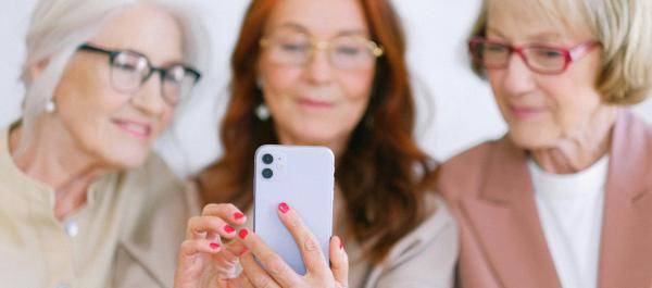 zdjęcie trzy starsze kobiety patrzą w jeden smartfon
