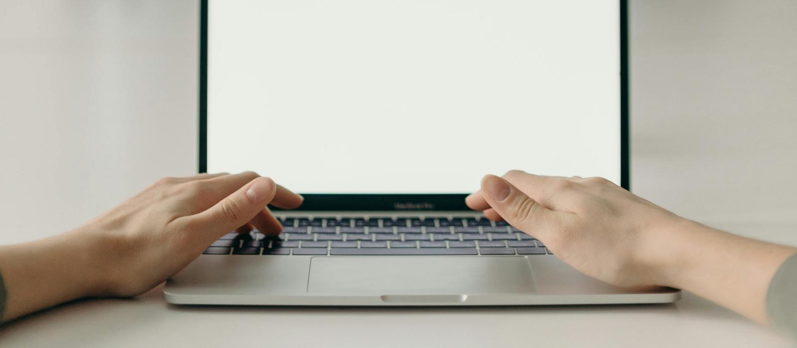 zdjęcie dłonie ułożone na klawiaturze laptopa w tle lustro